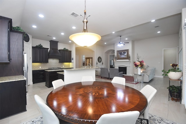 dining space with a fireplace, visible vents, ceiling fan, arched walkways, and recessed lighting
