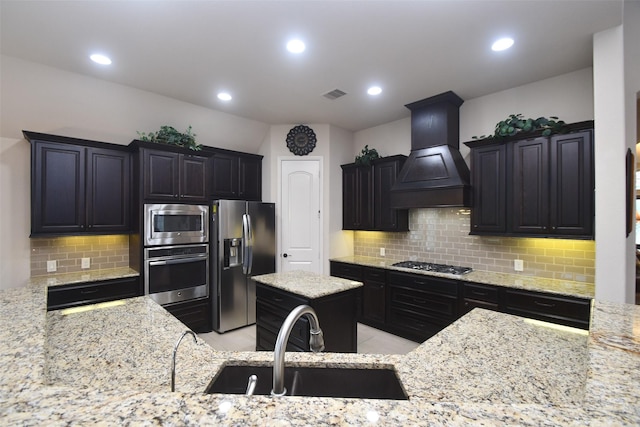 kitchen with light stone counters, custom exhaust hood, visible vents, a sink, and appliances with stainless steel finishes