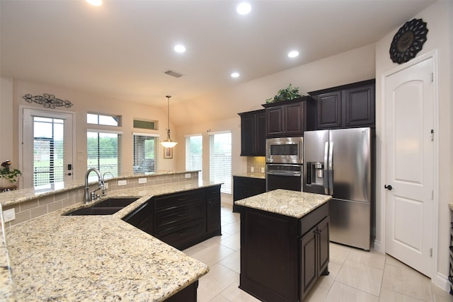 kitchen featuring a sink, stainless steel appliances, visible vents, a kitchen island, and tasteful backsplash