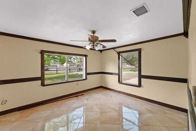 empty room with crown molding, a textured ceiling, a ceiling fan, baseboards, and visible vents
