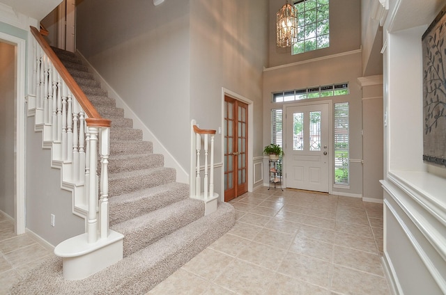 entryway featuring stairway, tile patterned floors, baseboards, a chandelier, and a high ceiling