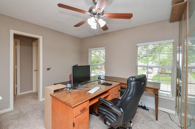 home office with baseboards, ceiling fan, and light colored carpet