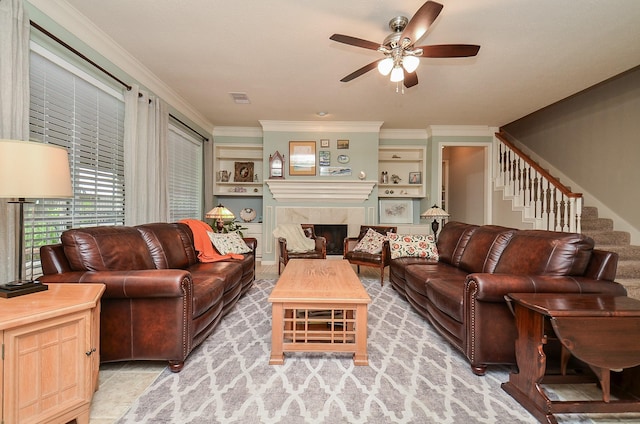 living area with crown molding, a fireplace, a ceiling fan, visible vents, and stairway