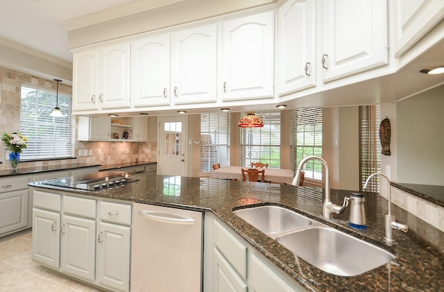 kitchen featuring a sink, cooktop, hanging light fixtures, and a healthy amount of sunlight
