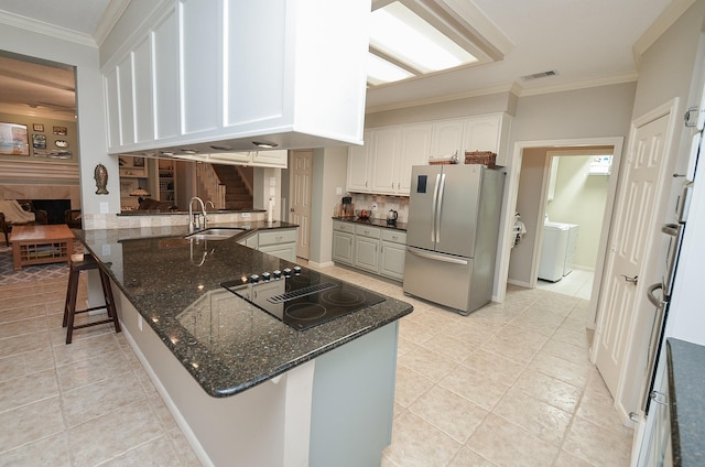 kitchen featuring crown molding, black electric stovetop, a sink, freestanding refrigerator, and decorative backsplash