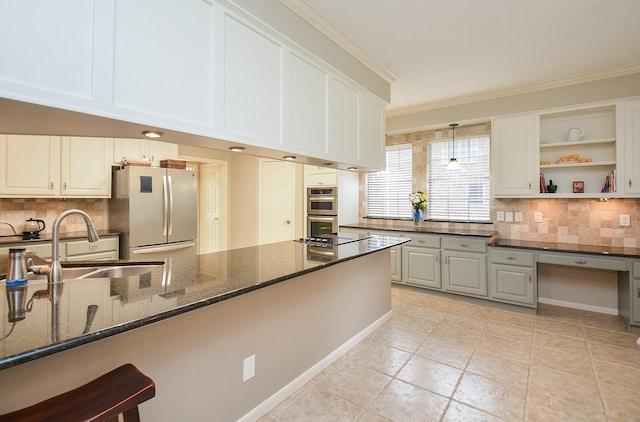 kitchen featuring backsplash, stainless steel appliances, a sink, and dark stone countertops