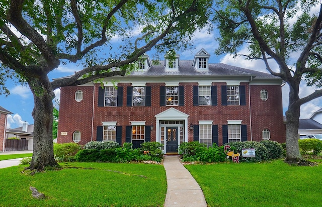 colonial house featuring brick siding and a front yard