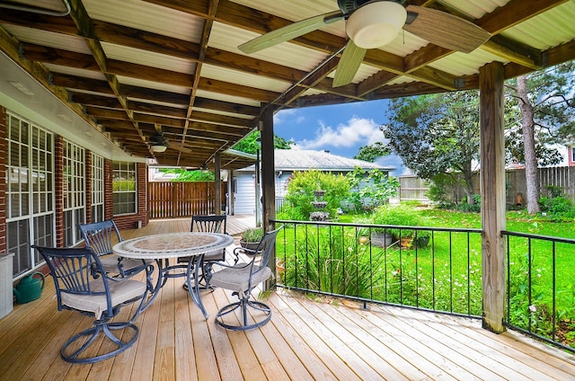 wooden deck featuring fence, a ceiling fan, outdoor dining area, and a yard