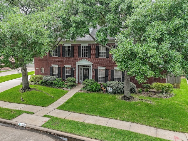 colonial inspired home with brick siding and a front lawn
