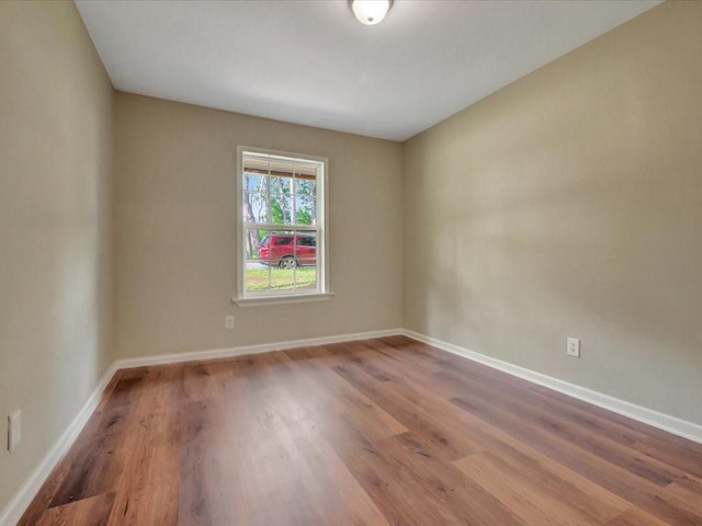 spare room featuring baseboards and wood finished floors