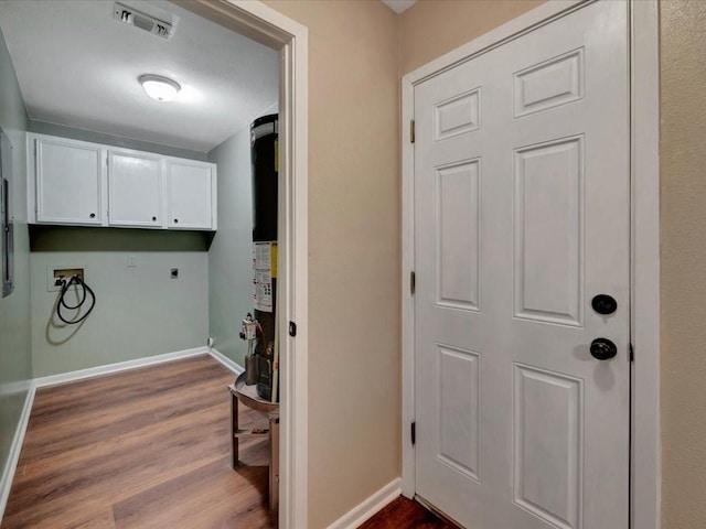 clothes washing area with electric dryer hookup, visible vents, cabinet space, baseboards, and dark wood-type flooring