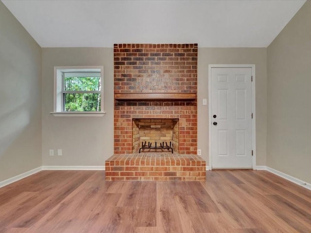 unfurnished living room with baseboards, a fireplace, and wood finished floors
