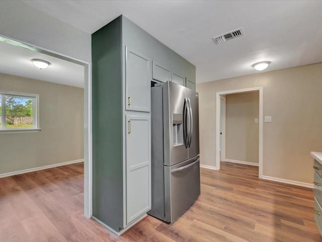 kitchen featuring baseboards, visible vents, light wood finished floors, and stainless steel fridge with ice dispenser