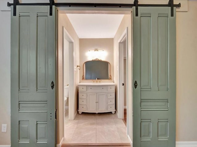 bathroom with baseboards, tile patterned floors, toilet, and vanity