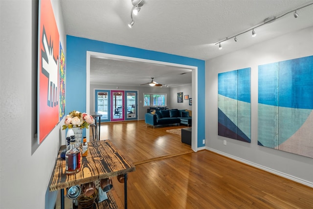 4811 Saxon St, Bellaire, TX 77401 - hall featuring a textured ceiling, baseboards, rail lighting, and wood finished floors