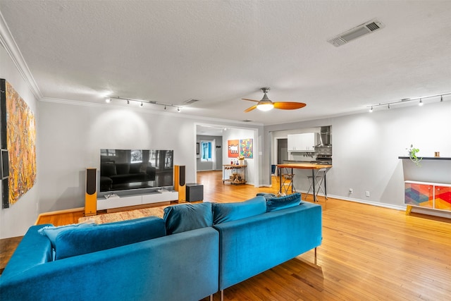 4811 Saxon St, Bellaire, TX 77401 - living room with crown molding, a textured ceiling, rail lighting, a ceiling fan, and visible vents
