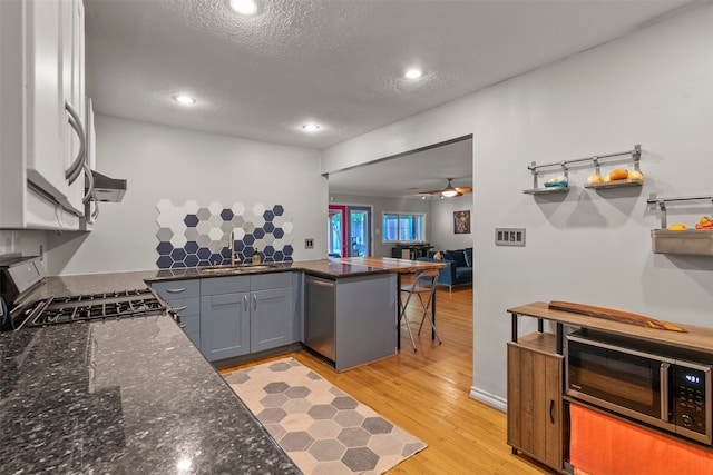 4811 Saxon St, Bellaire, TX 77401 - kitchen with a peninsula, a textured ceiling, a sink, dark stone countertops, and stainless steel appliances