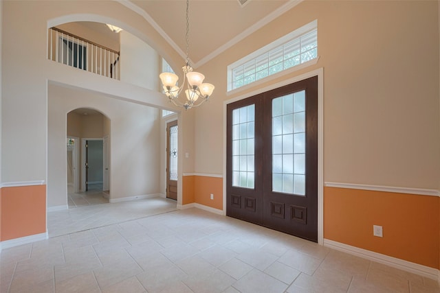 entrance foyer featuring french doors, arched walkways, plenty of natural light, and a high ceiling