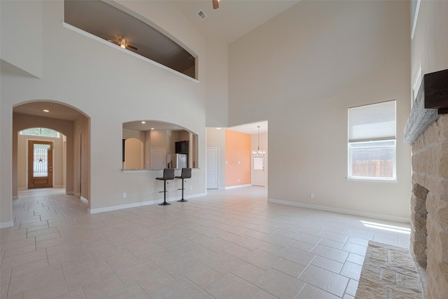 unfurnished living room featuring baseboards, a high ceiling, and a wealth of natural light