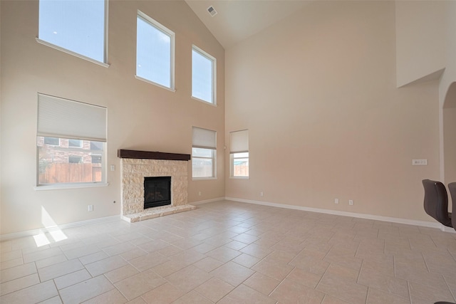 unfurnished living room featuring high vaulted ceiling, baseboards, light tile patterned flooring, and a stone fireplace