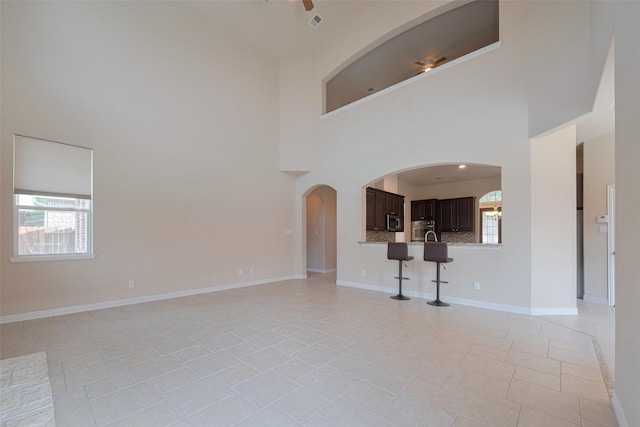 unfurnished living room with baseboards and a high ceiling