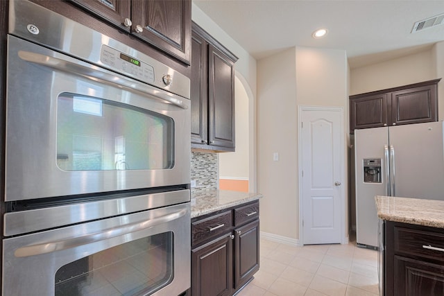kitchen with appliances with stainless steel finishes, visible vents, light tile patterned flooring, and dark brown cabinets