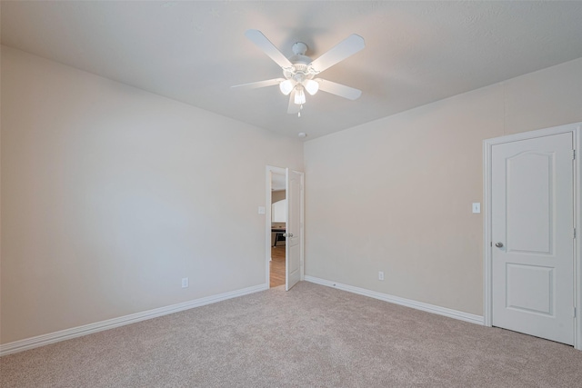 unfurnished room with baseboards, a ceiling fan, and light carpet