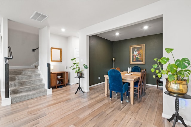 dining area with visible vents, baseboards, stairway, and light wood-type flooring