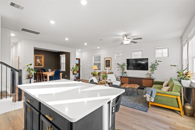 kitchen featuring ceiling fan, a kitchen island, visible vents, light countertops, and light wood-style flooring
