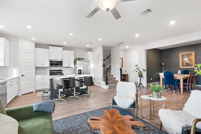 living area featuring visible vents, recessed lighting, and stairs