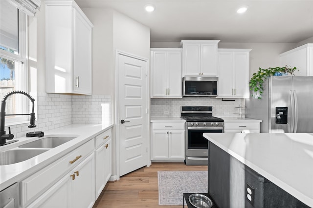 kitchen with a sink, white cabinetry, appliances with stainless steel finishes, and light countertops