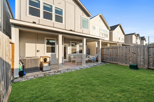 back of property featuring a yard, a patio, central AC, and a fenced backyard