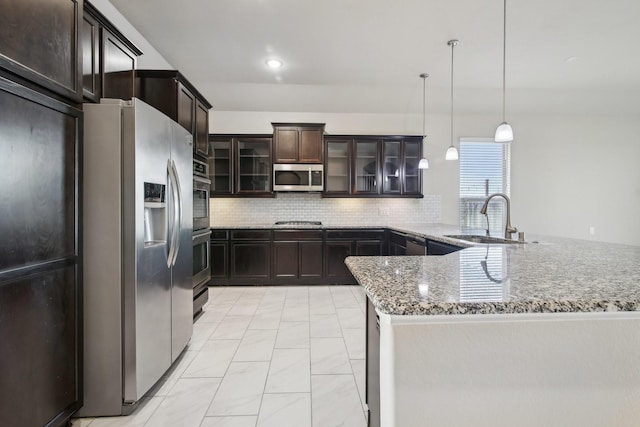 4310 Treccia Ct, Katy, TX 77493 - kitchen featuring appliances with stainless steel finishes, a sink, a peninsula, light stone countertops, and backsplash