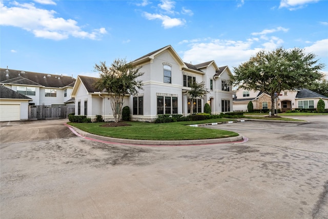 view of front of house with fence, a residential view, a front lawn, and stucco siding
