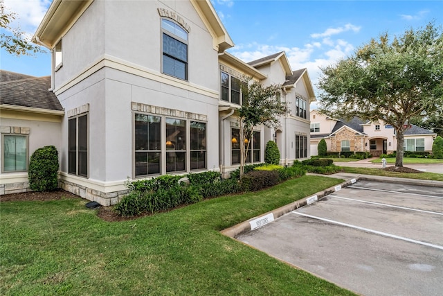 exterior space with a lawn, stucco siding, and uncovered parking