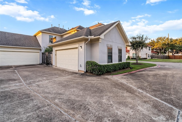 view of side of home with fence, a garage, driveway, and stucco siding