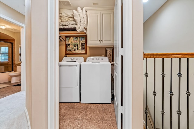 clothes washing area featuring visible vents, cabinet space, and washing machine and dryer