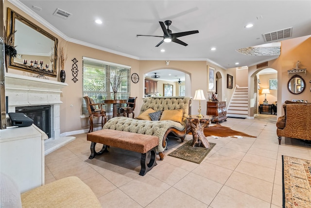 living room featuring a ceiling fan, arched walkways, visible vents, and light tile patterned floors