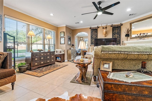 tiled living area with crown molding, arched walkways, ceiling fan, and visible vents
