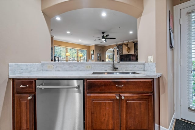 kitchen featuring arched walkways, tasteful backsplash, stainless steel dishwasher, a sink, and light countertops