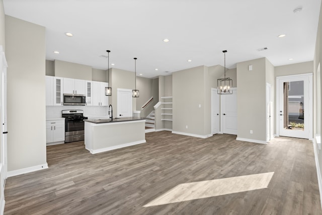 kitchen featuring white cabinets, stainless steel appliances, wood finished floors, and a notable chandelier