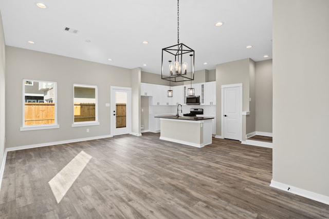 unfurnished living room featuring a chandelier, visible vents, baseboards, and a sink