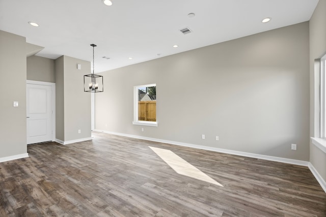 interior space featuring a notable chandelier, baseboards, visible vents, and wood finished floors
