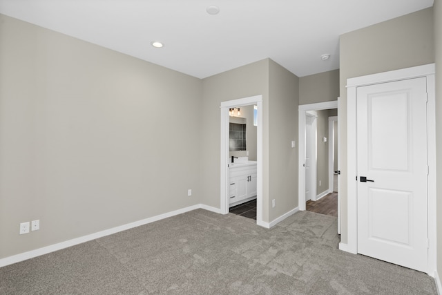 unfurnished bedroom featuring carpet flooring, ensuite bath, and baseboards