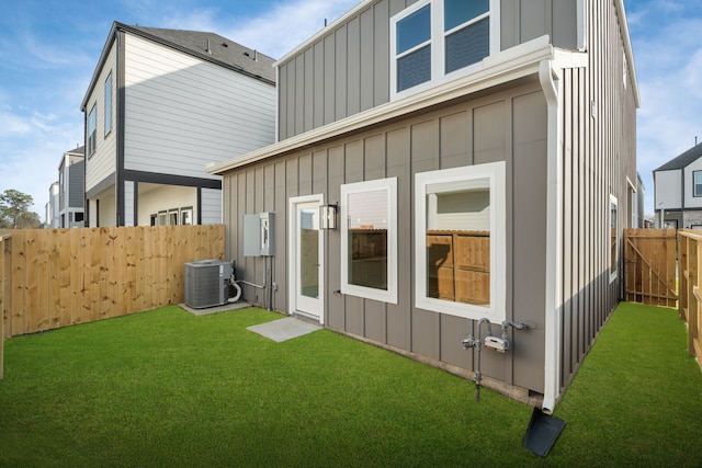 back of property featuring a yard, board and batten siding, cooling unit, and a fenced backyard