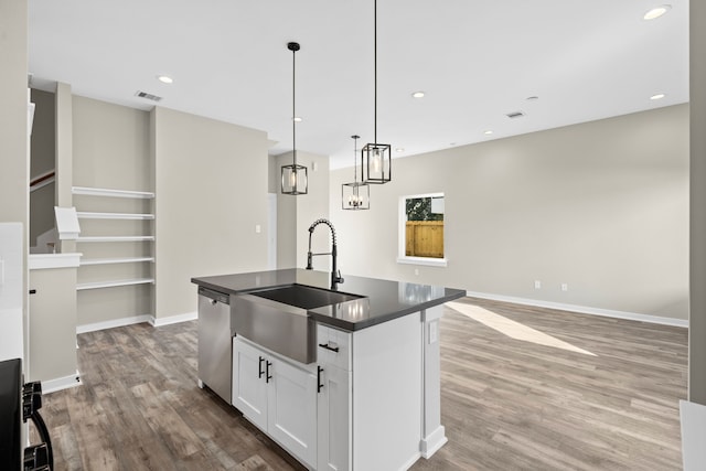 kitchen with a sink, wood finished floors, white cabinets, stainless steel dishwasher, and dark countertops