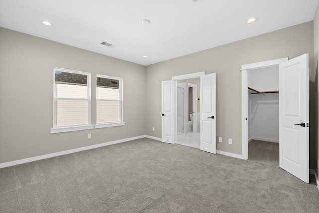 unfurnished bedroom with carpet, visible vents, baseboards, and a spacious closet