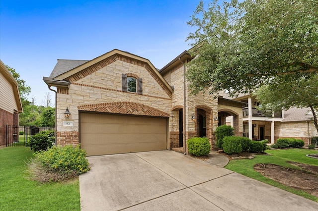 french country style house with fence, driveway, a front lawn, and stone siding