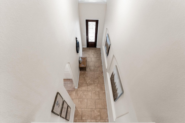 hallway with a high ceiling and light tile patterned flooring