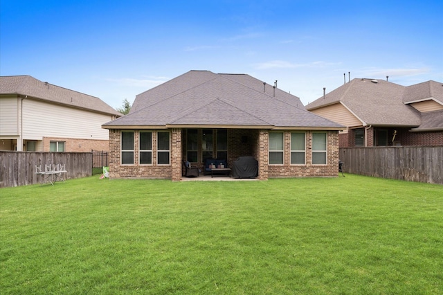 rear view of house featuring brick siding, a fenced backyard, and a lawn